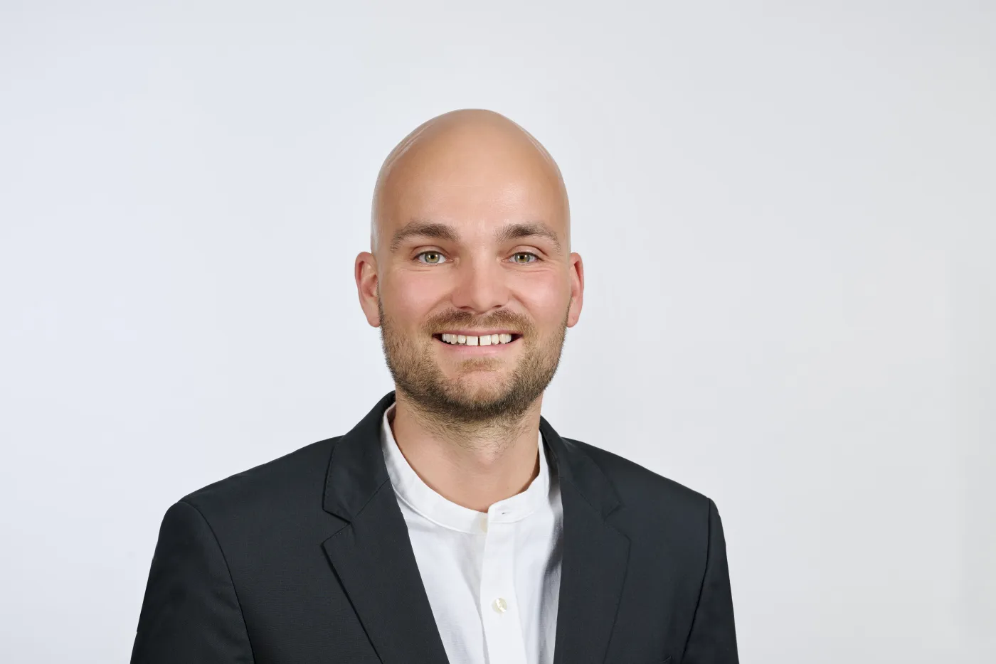Birk Anders im schwarzen Sakko vor hellem Hintergrund
